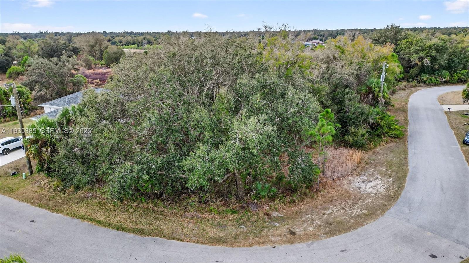 An aerial view shows a vacant, tree-covered corner lot bordered by paved roads — 0 NELL RD, North Port FL 34288, NORTH PORT, FL