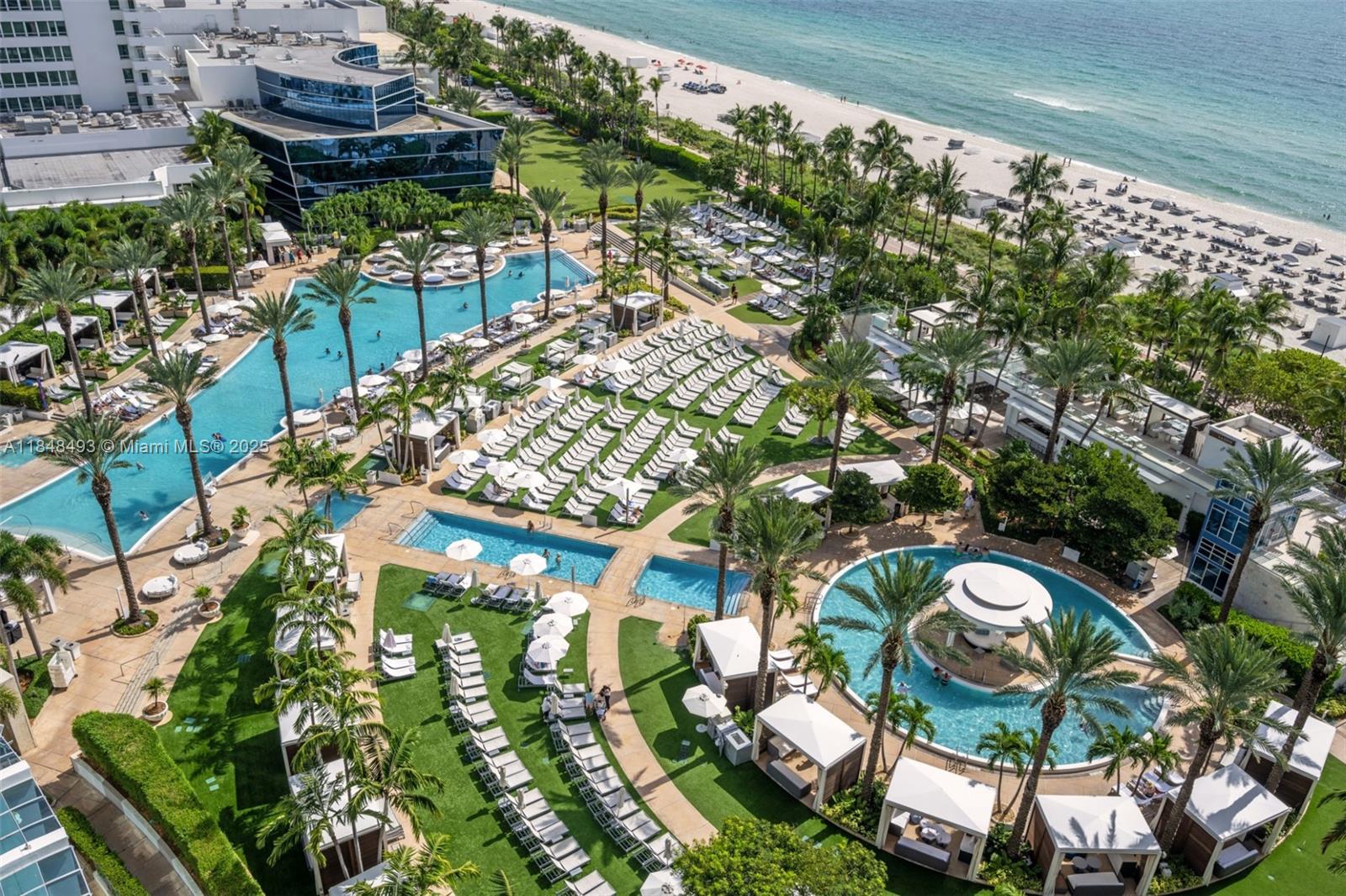 An aerial view shows a resort pool complex with lounge chairs, cabanas, and beach access — 4391 Collins Ave # 1605, Miami Beach FL 33140, MIAMI BEACH, FL