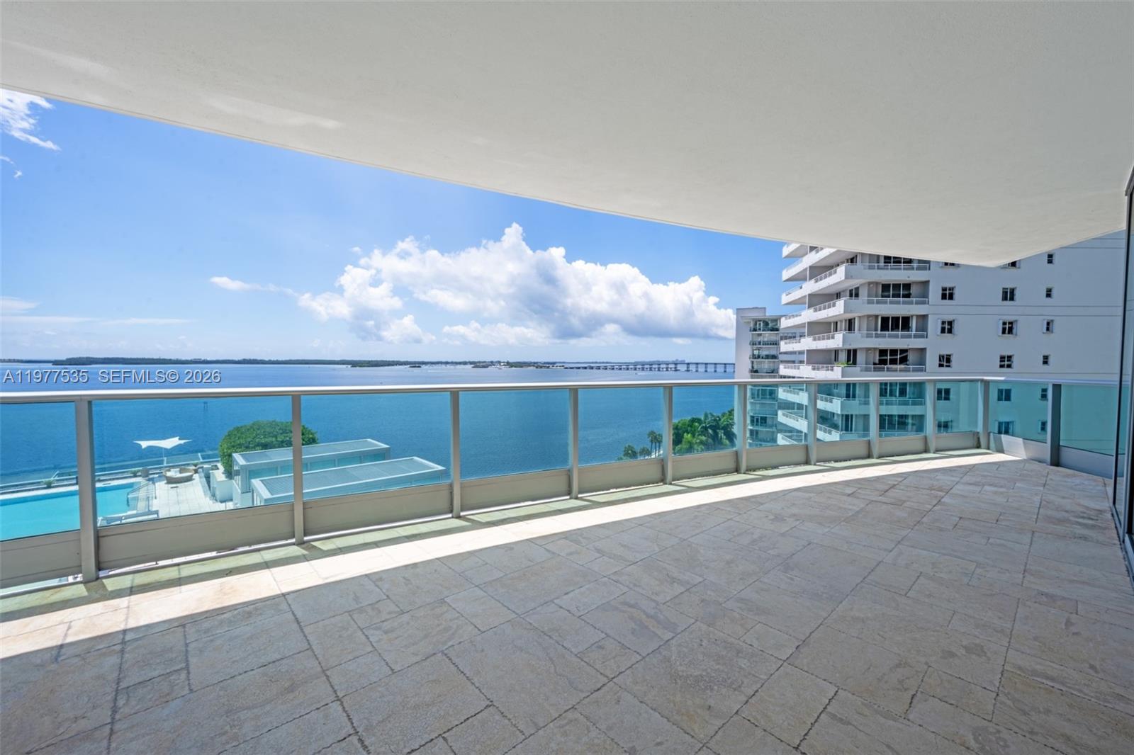 A spacious balcony with stone tile flooring overlooks the ocean and a neighboring high-rise building — 1331 Brickell Bay Dr # 911, Miami FL 33131, MIAMI, FL