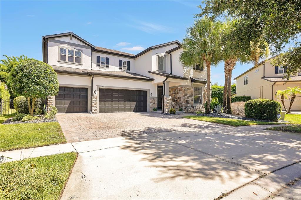 A two-story house features a stone facade, a three-car garage, and a paved driveway — 9443 ROYAL ESTATES BOULEVARD, ORLANDO, FL