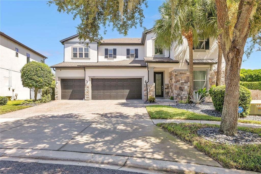 A two-story house with a three-car garage, stone accents, and a paved driveway — 9443 ROYAL ESTATES BOULEVARD, ORLANDO, FL