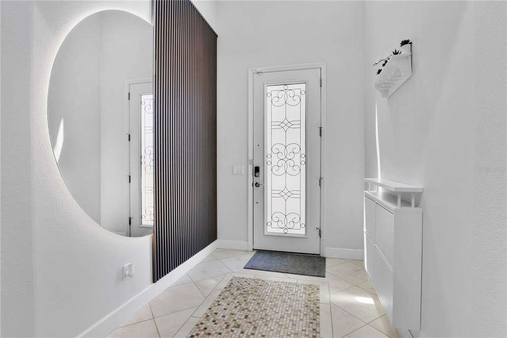 An entryway features a large circular backlit mirror, vertical wood slats, and a glass-paneled door — 9443 ROYAL ESTATES BOULEVARD, ORLANDO, FL