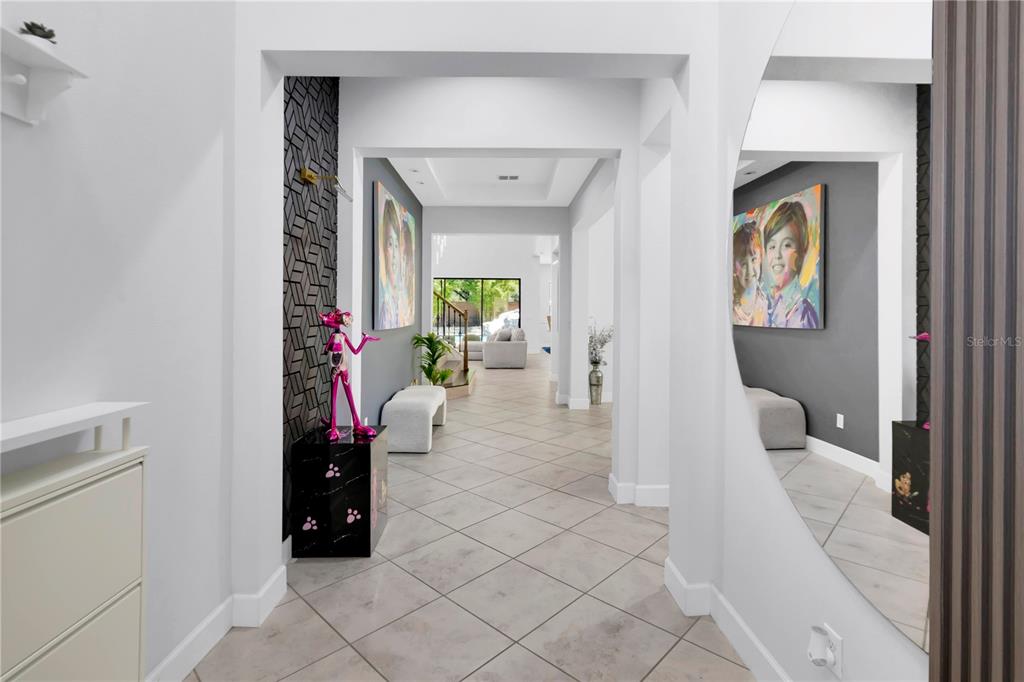 A bright entryway features tiled floors, a large circular mirror, and a pink panther statue — 9443 ROYAL ESTATES BOULEVARD, ORLANDO, FL