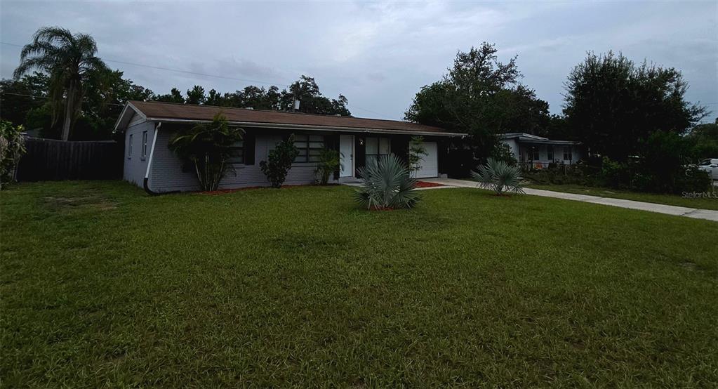 A single-story gray brick house with a brown roof and a front lawn — 8709 N RENFREW PLACE, TAMPA, FL