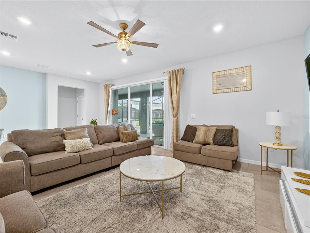 A living room features a brown sofa, a loveseat, a marble coffee table, and a ceiling fan — 3044 MAHALO DRIVE, DAVENPORT, FL