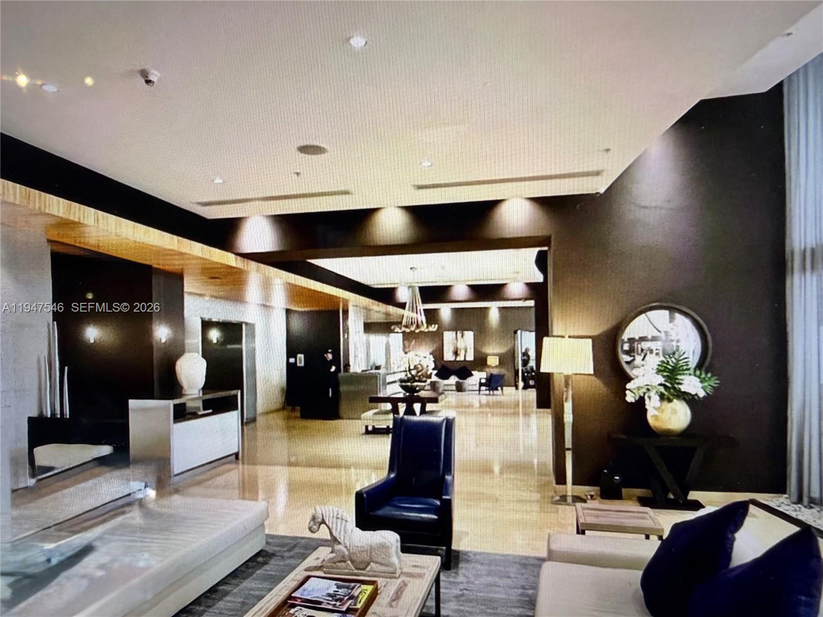 A spacious, modern lobby features dark walls, recessed lighting, polished floors, and contemporary seating areas — 60 SW 13th St # 3214, Miami FL 33130, MIAMI, FL