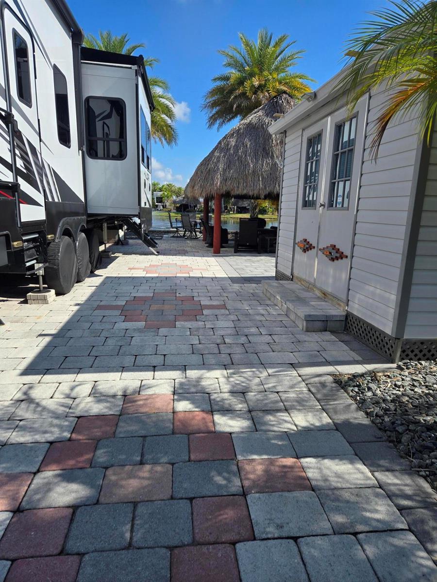 A paved patio area sits between a parked recreational vehicle and a small storage shed — 609 SW 42nd Cove, Okeechobee FL 34974, OKEECHOBEE, FL