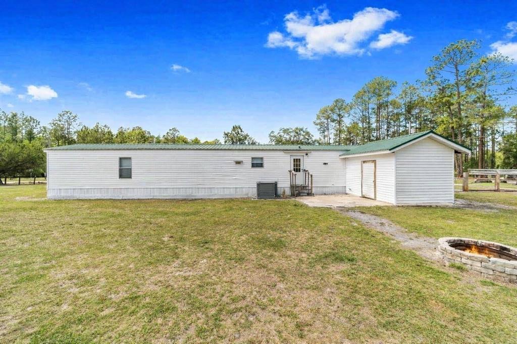 A white mobile home with a green metal roof sits on a grassy lot — 13261 NE 155TH LANE, FORT MC COY, FL
