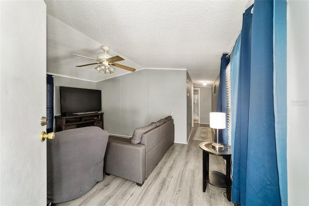 A living room with gray walls, wood-look flooring, a gray sofa, and a ceiling fan — 13261 NE 155TH LANE, FORT MC COY, FL