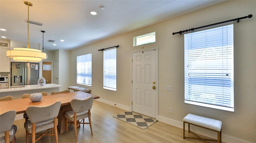A dining area with a wooden table, light wood flooring, and an adjacent entryway — 1102 BERKMAN CIRCLE, SANFORD, FL