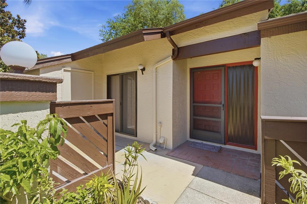 The exterior view shows a house entrance with a red door, sliding glass door, and fencing — 2909 FIG COURT, PALM HARBOR, FL
