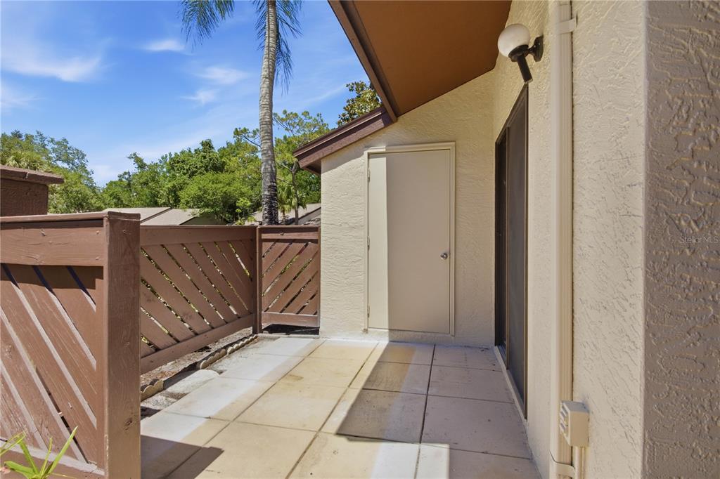 A patio with a brown wooden fence, a storage closet door, and sliding glass doors — 2909 FIG COURT, PALM HARBOR, FL