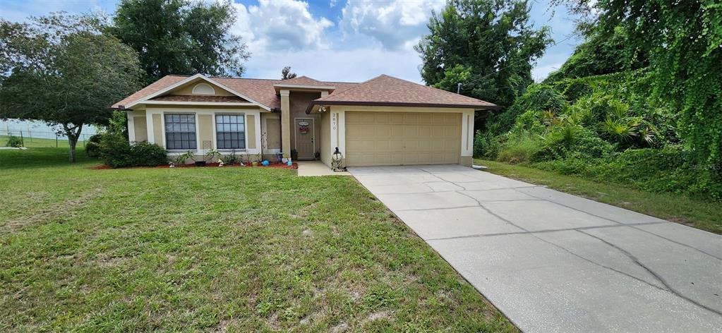 A single-story house with a tan exterior, a two-car garage, and a concrete driveway — 2870 IDLEWEISE DRIVE, DELTONA, FL
