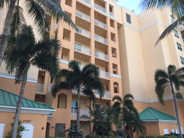 A multi-story tan apartment building with balconies and palm trees in the foreground — 2060 MATECUMBE KEY ROAD UNIT 2105, PUNTA GORDA, FL