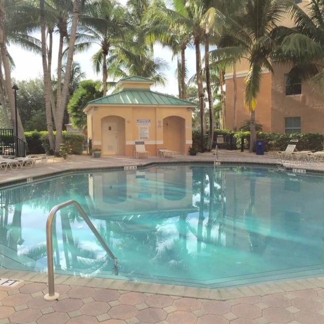 A swimming pool sits in front of a small pavilion surrounded by palm trees — 2060 MATECUMBE KEY ROAD UNIT 2105, PUNTA GORDA, FL