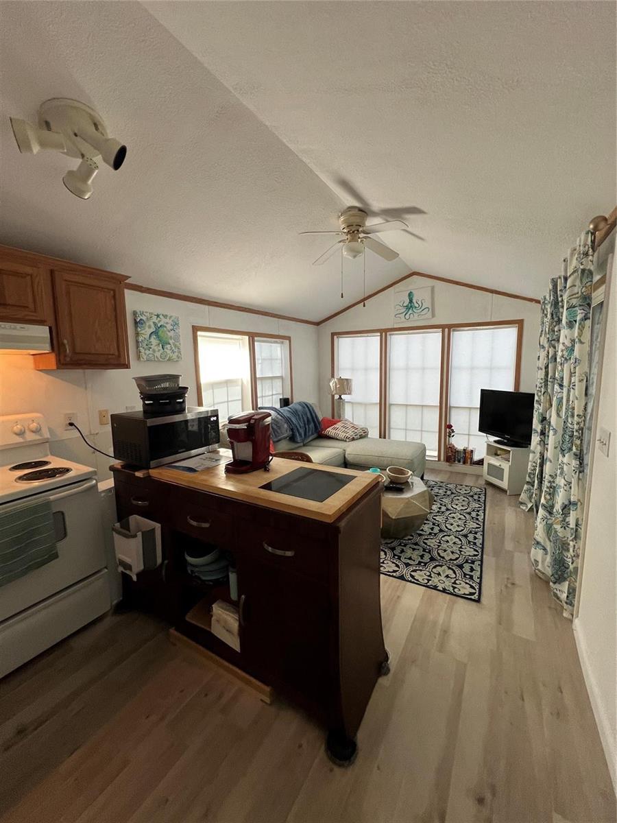 A kitchen with a wooden island and stove opens into a living area with windows — 6445 SE 51st Street, Okeechobee FL 34974, OKEECHOBEE, FL