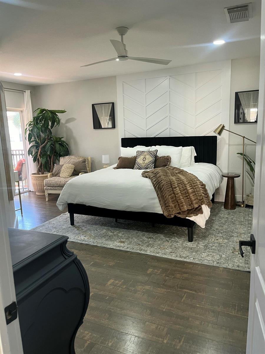 A hallway features a wooden console table, a large abstract painting, and an arched wall mirror — 1910 Belmont Place, Boynton Beach FL 33436, BOYNTON BEACH, FL