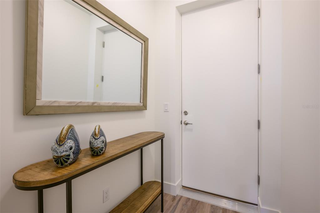 A hallway features a wooden console table, two decorative owl figurines, and a large mirror — 1703 N TAMIAMI TRAIL UNIT 205, SARASOTA, FL