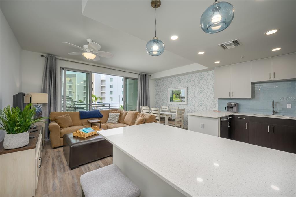 An open-concept living and kitchen area features a white quartz island, brown sofa, and dining set — 1703 N TAMIAMI TRAIL UNIT 205, SARASOTA, FL