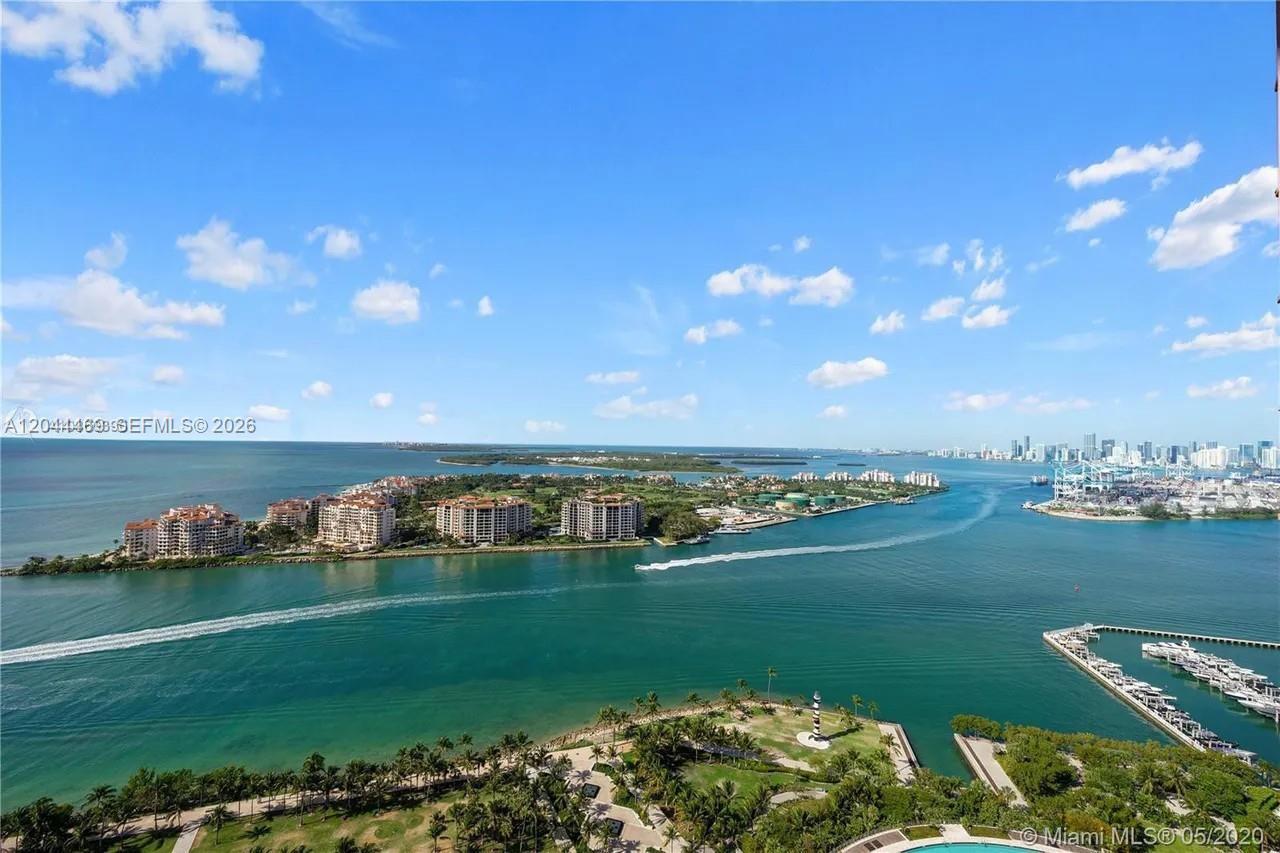 An elevated view of a bay with high-rise buildings, a park, and a distant city skyline — 300 S Pointe Dr # 3604, Miami Beach FL 33139, MIAMI BEACH, FL