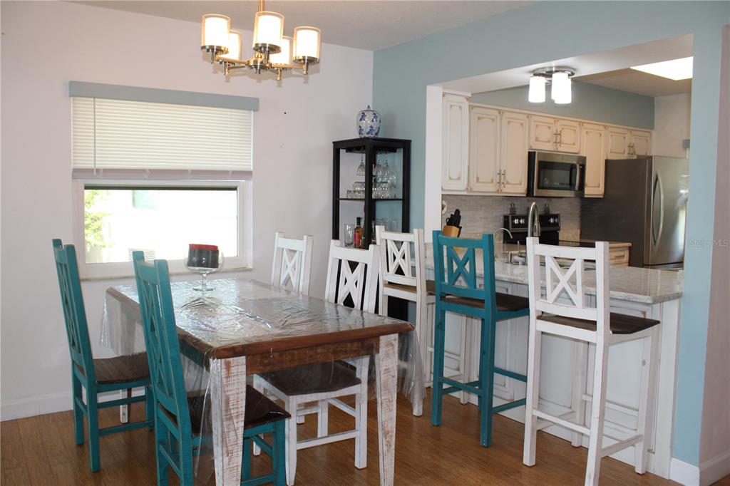A dining area with a wooden table and chairs sits adjacent to a kitchen island — 1813 MARINER DRIVE UNIT 151, TARPON SPRINGS, FL