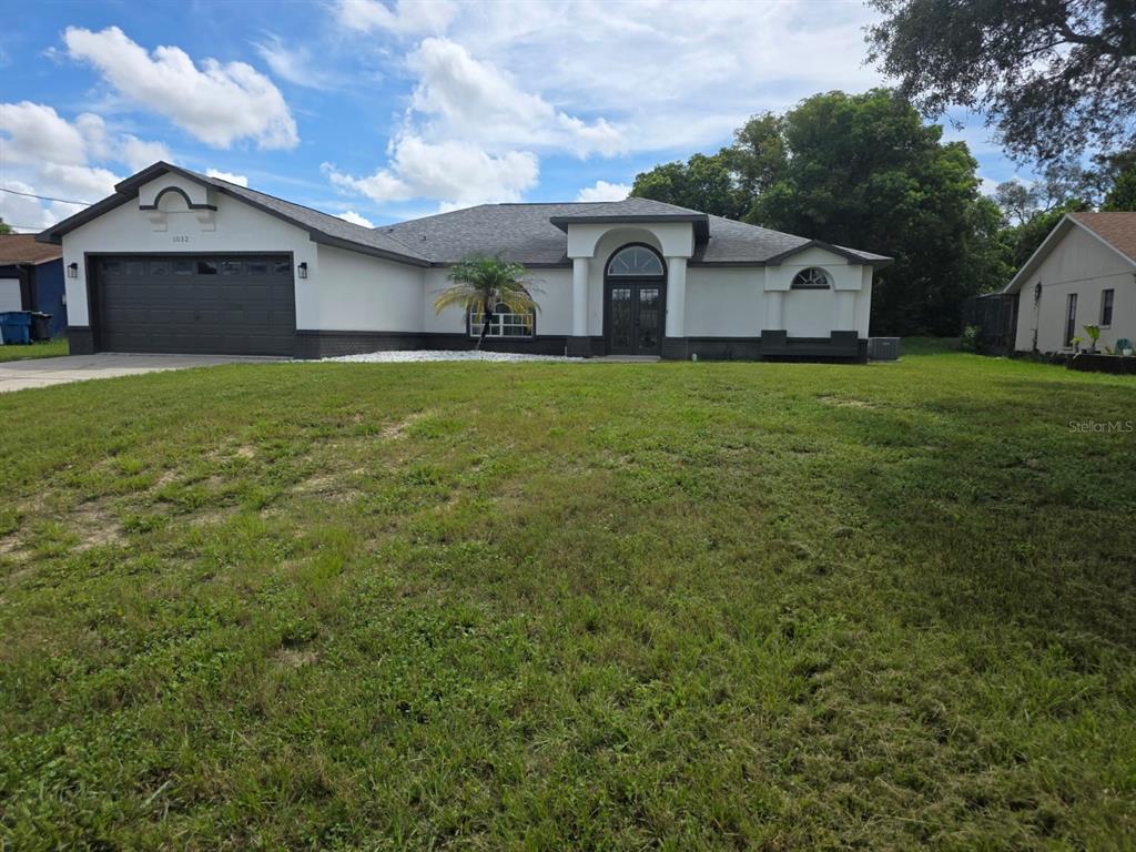 A single-story house with white stucco walls, dark trim, and a two-car garage — 1032 CONCERT AVENUE, SPRING HILL, FL