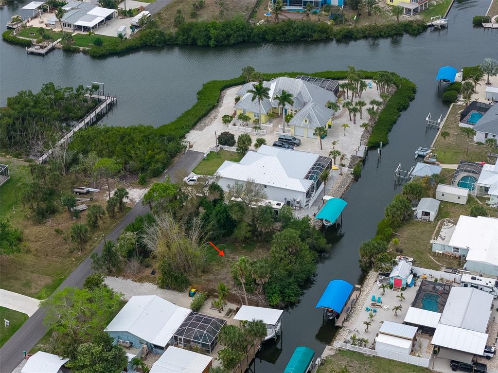 An aerial view shows a vacant waterfront lot marked with an arrow near residential homes — 1132 ANDREWS STREET, ENGLEWOOD, FL