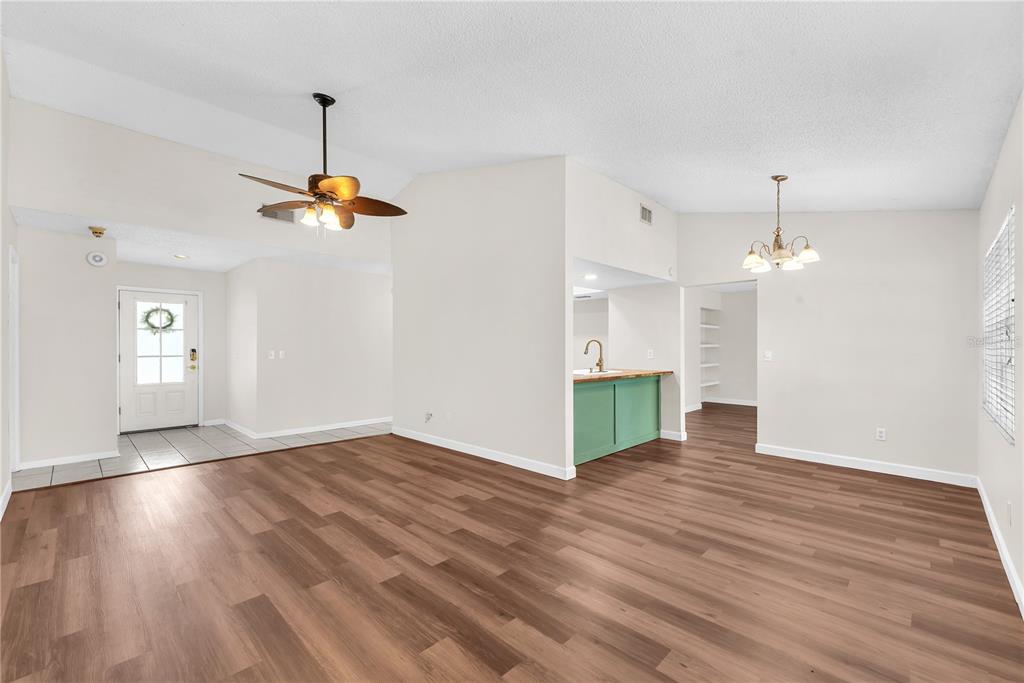 An open-concept living and dining area features wood-look flooring, a ceiling fan, and a kitchen — 3619 ORANGEPOINTE ROAD, VALRICO, FL