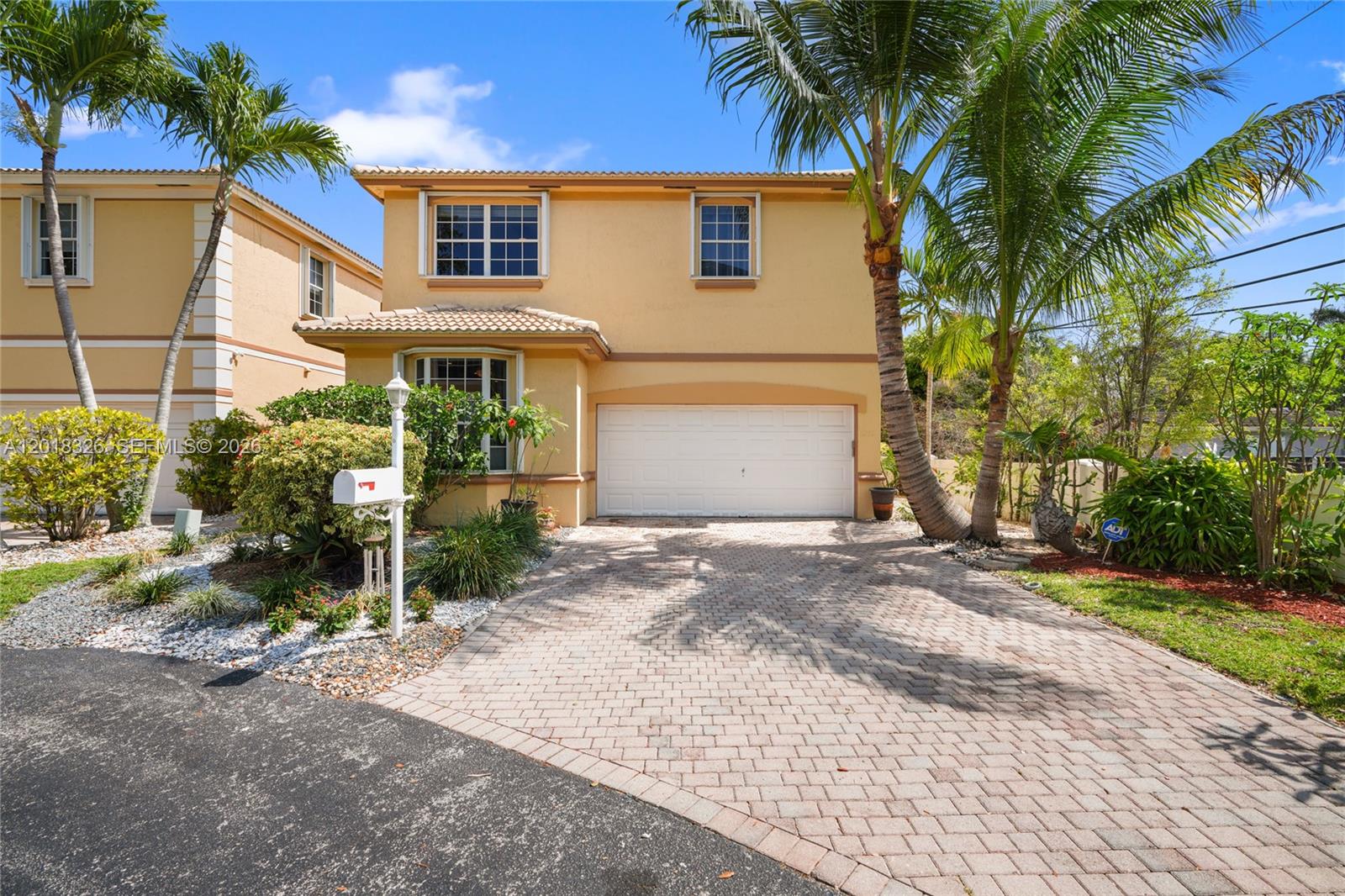 A two-story yellow stucco house features a paved driveway, a garage, and palm trees — 1282 Grant Ct, Hollywood FL 33019, HOLLYWOOD, FL