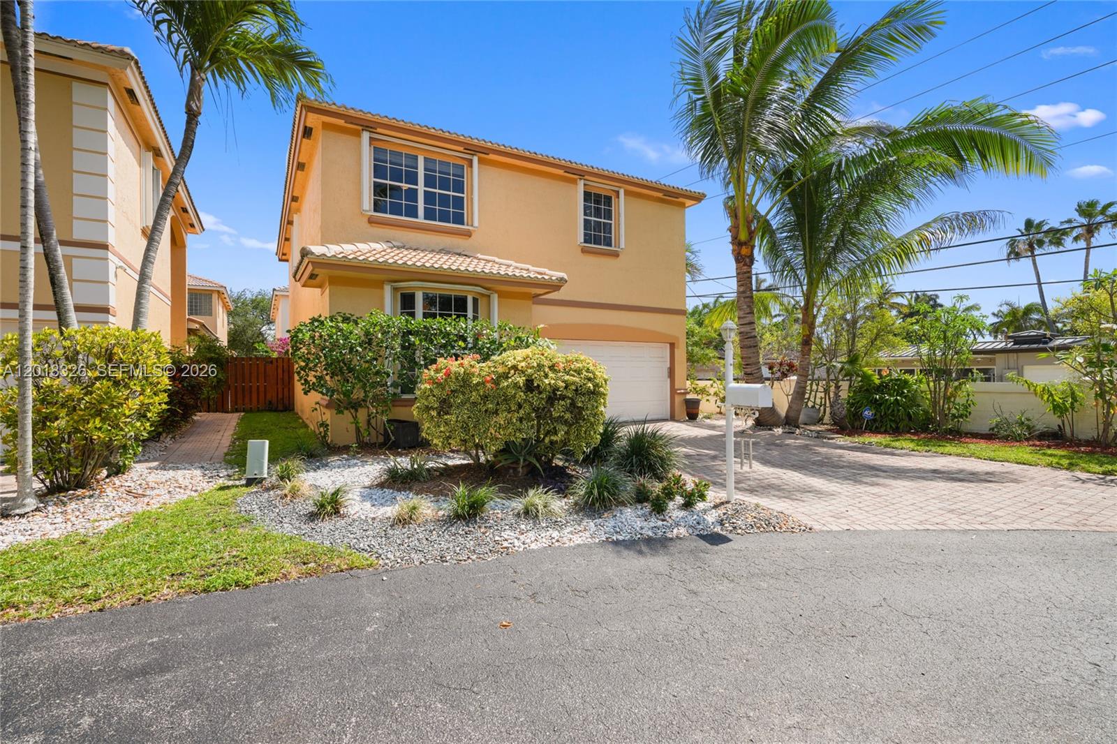 A two-story yellow stucco house features a paved driveway, a garage, and palm trees — 1282 Grant Ct, Hollywood FL 33019, HOLLYWOOD, FL