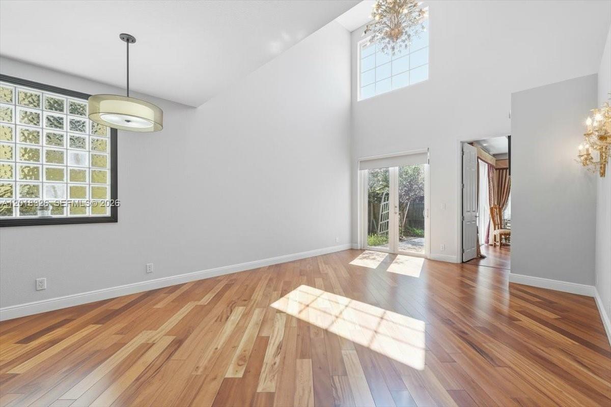 A dining room with high ceilings, hardwood floors, a glass block wall, and French doors — 1282 Grant Ct, Hollywood FL 33019, HOLLYWOOD, FL