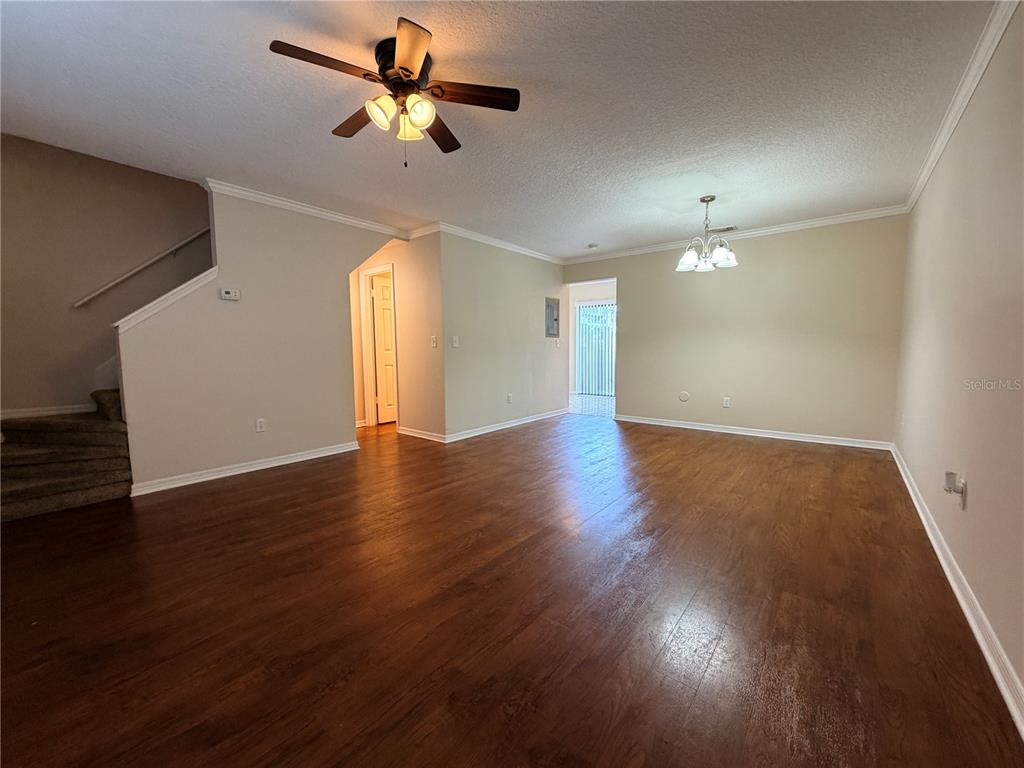 An open-concept living and dining area features wood-look flooring, a ceiling fan, and stairs — 3220 OAK LAWN PLACE PLACE UNIT 210, WINTER PARK, FL