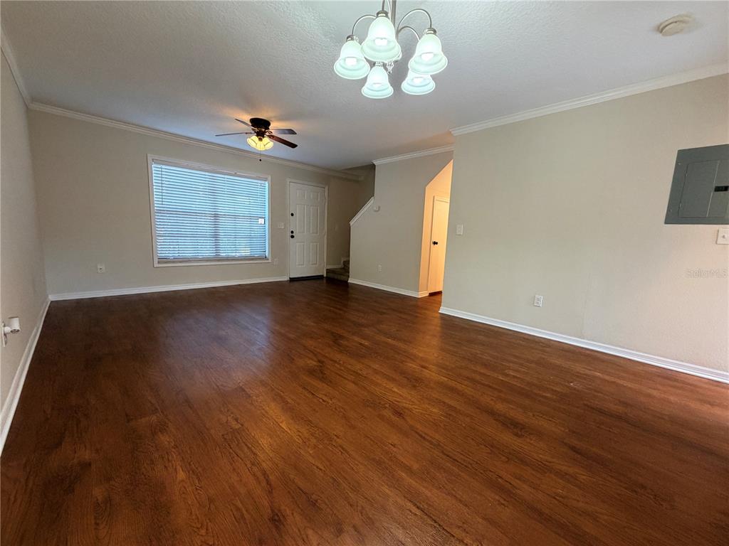 A living room features wood-look flooring, a ceiling fan, a chandelier, and a front door — 3220 OAK LAWN PLACE PLACE UNIT 210, WINTER PARK, FL