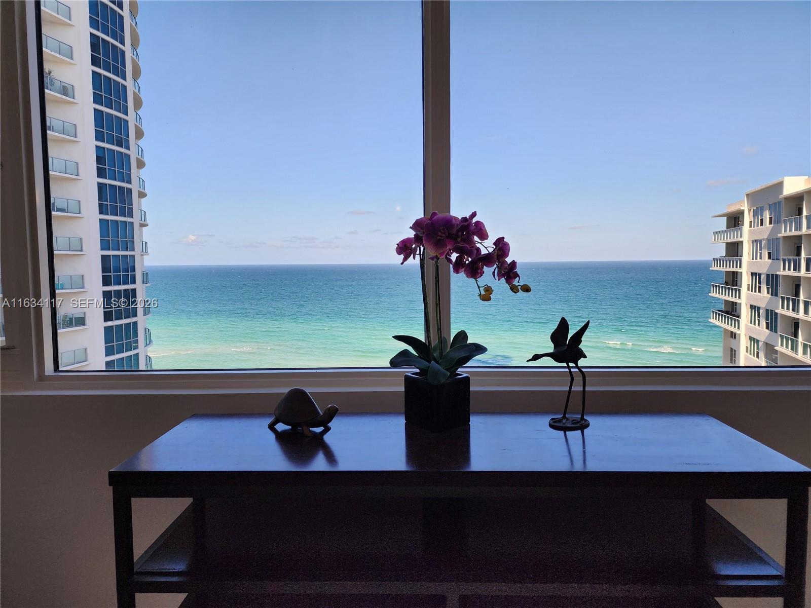 A console table with decorative items sits before a large window overlooking the ocean — 3505 S Ocean Dr # 1406, Hollywood FL 33019, HOLLYWOOD, FL