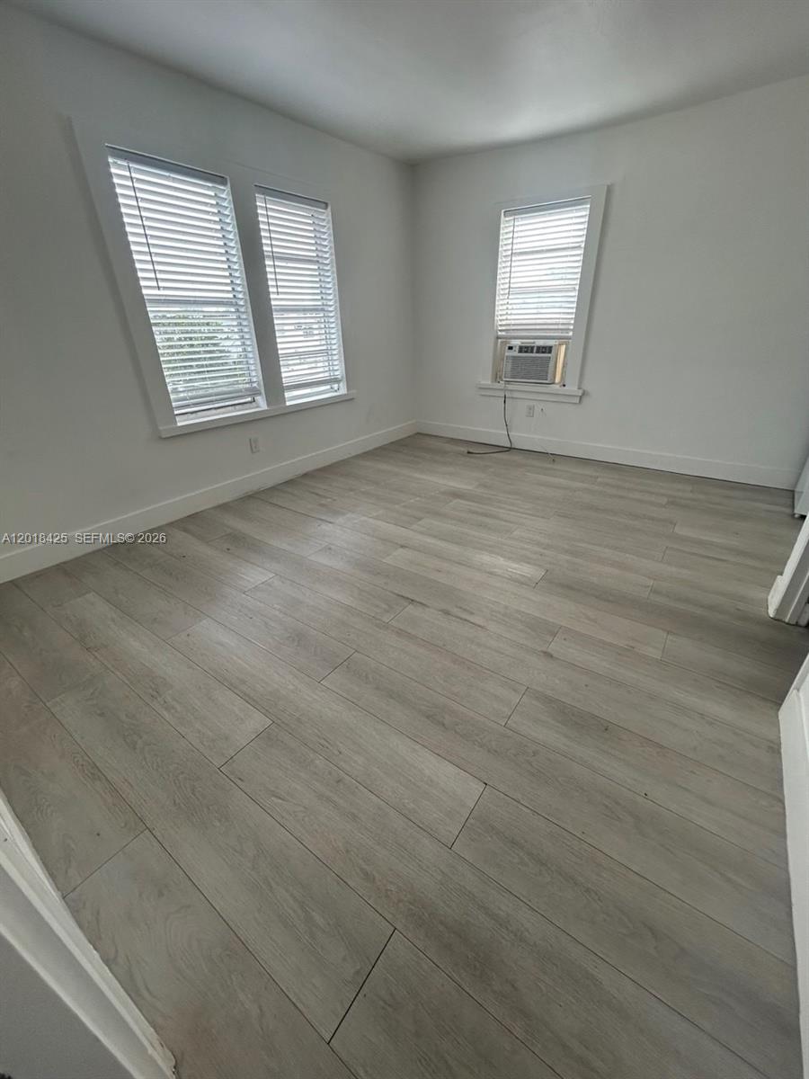 An empty room features light wood-look flooring, white walls, and three windows with blinds — 967 SW 5th St # 14, Miami FL 33130, MIAMI, FL