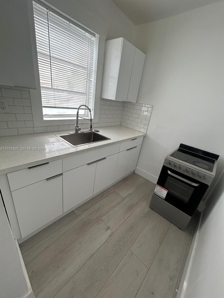A kitchen features white cabinets, a quartz countertop, a stainless steel sink, and subway tile — 967 SW 5th St # 14, Miami FL 33130, MIAMI, FL