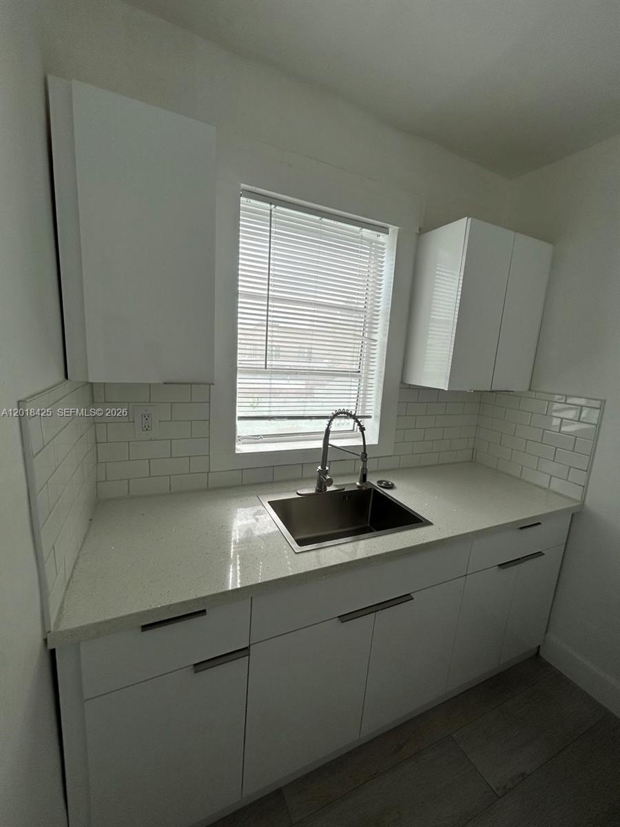 A white refrigerator stands in a room adjacent to a small kitchen with light flooring — 967 SW 5th St # 14, Miami FL 33130, MIAMI, FL