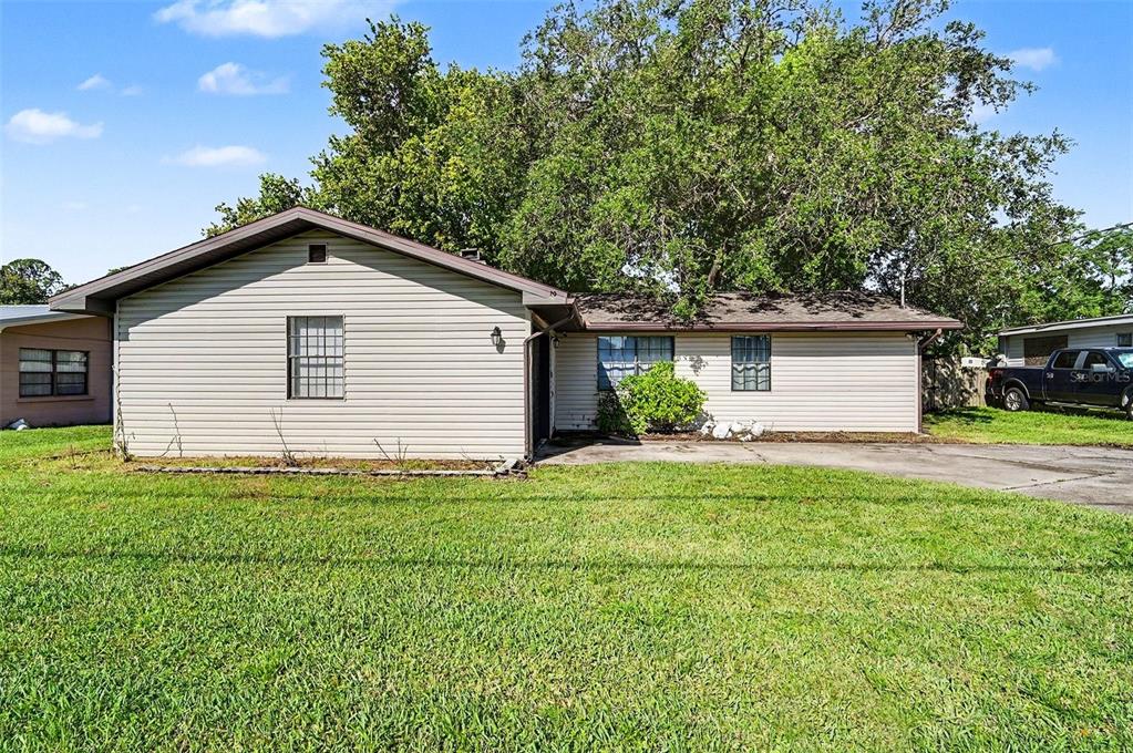 A single-story house with beige horizontal siding and a large tree in the front yard — 1980 OLD DIXIE HIGHWAY, TITUSVILLE, FL