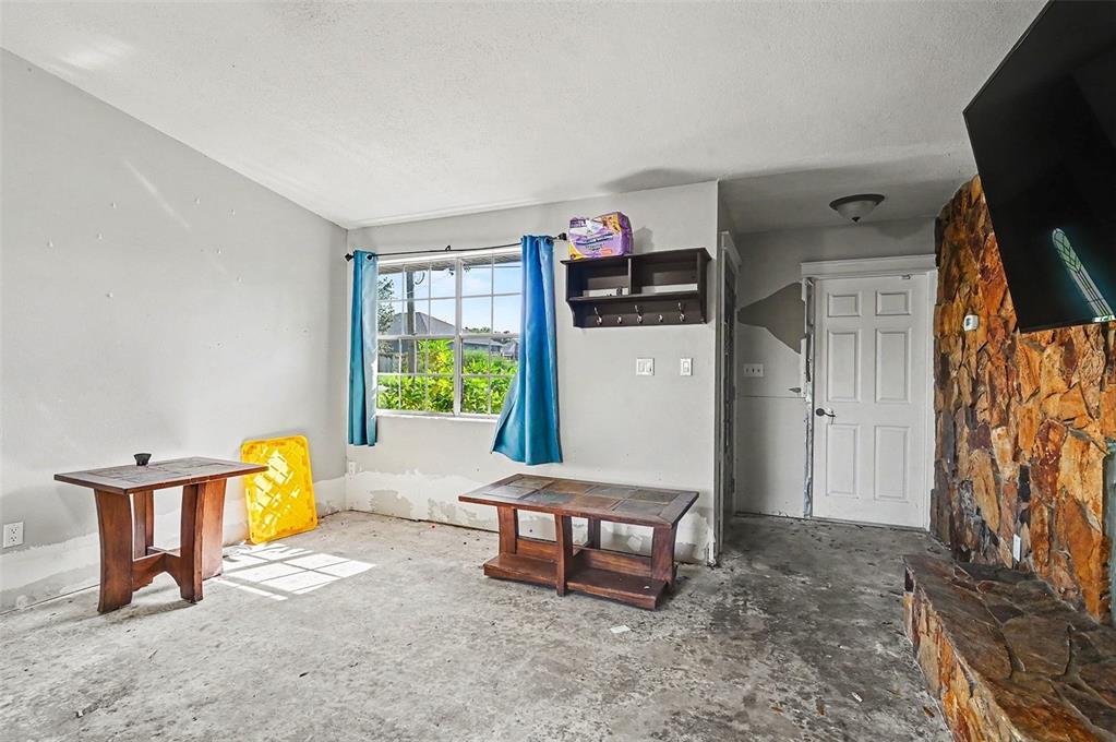 A room with a concrete floor, a stone fireplace, a window, and two wooden tables — 1980 OLD DIXIE HIGHWAY, TITUSVILLE, FL