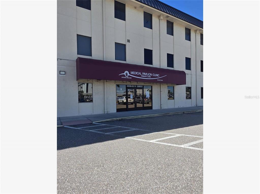 The exterior of a multi-story commercial building features a maroon awning over the clinic entrance — 2525 HARBOR BOULEVARD UNIT 101, PORT CHARLOTTE, FL