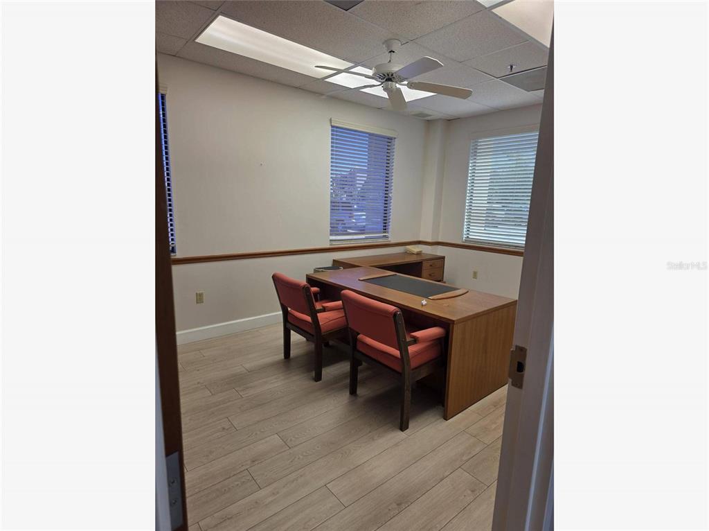 An office room features light wood-look flooring, two orange chairs, and a wooden desk — 2525 HARBOR BOULEVARD UNIT 101, PORT CHARLOTTE, FL