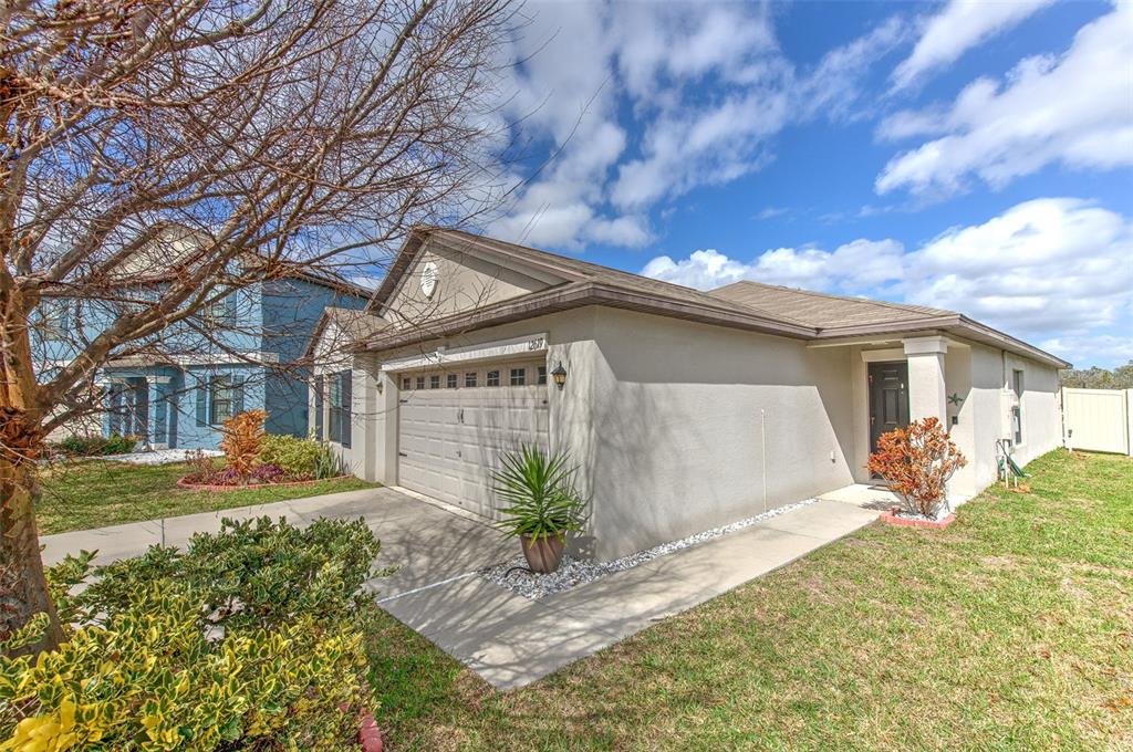 A single-story house with a beige stucco exterior, a two-car garage, and a front walkway — 12619 LEMON PEPPER DRIVE, RIVERVIEW, FL