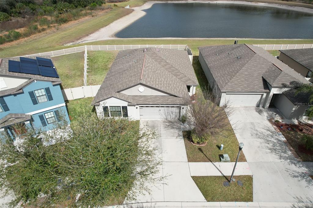 An aerial view shows a suburban house with a gray roof and driveway near a pond — 12619 LEMON PEPPER DRIVE, RIVERVIEW, FL