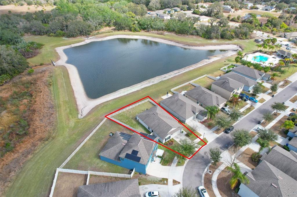An aerial view shows a single-family home with a fenced backyard bordering a pond — 12619 LEMON PEPPER DRIVE, RIVERVIEW, FL