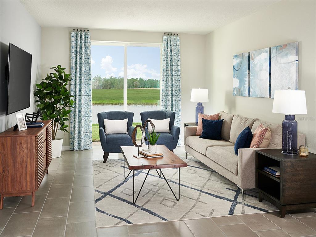 A living room features a beige sofa, two blue armchairs, a coffee table, and patio views — 3940 GIORGIO DRIVE, WINTER HAVEN, FL