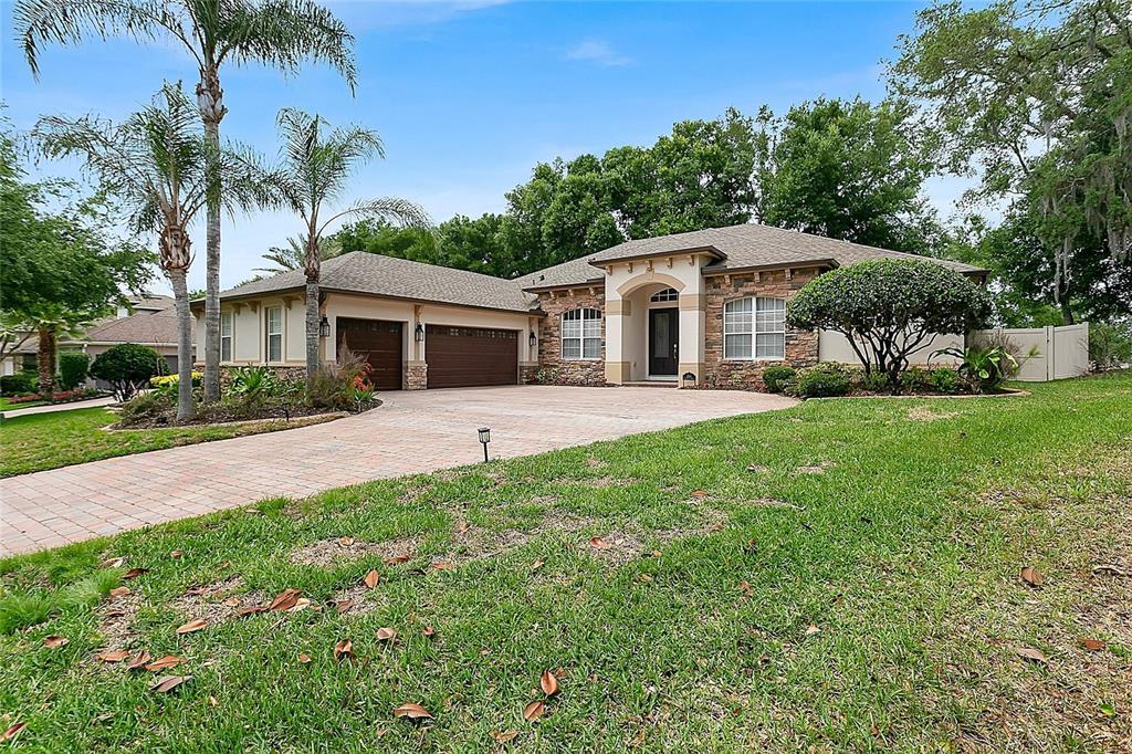 A single-story house with a stone facade, a paved driveway, and palm trees — 6361 BORDEAUX CIRCLE, SANFORD, FL