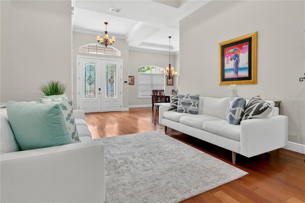 A living room features white sofas, a patterned area rug, and hardwood floors — 6361 BORDEAUX CIRCLE, SANFORD, FL