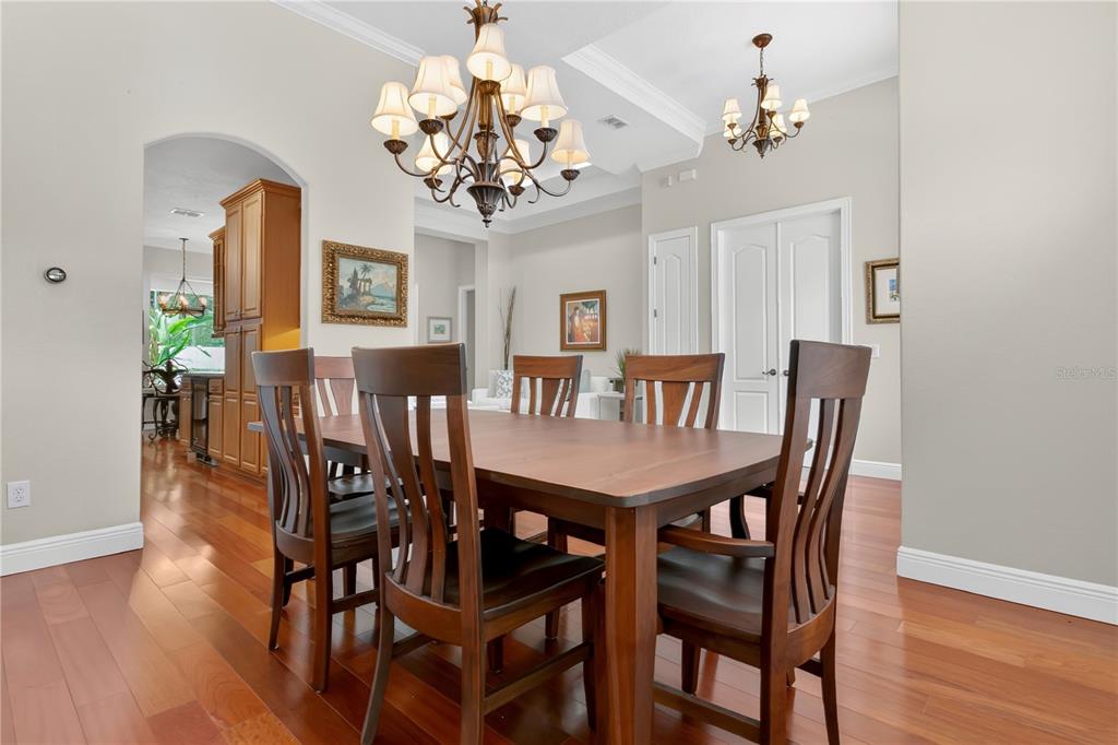 A dining room features a wooden table, chairs, hardwood floors, and two hanging chandeliers — 6361 BORDEAUX CIRCLE, SANFORD, FL