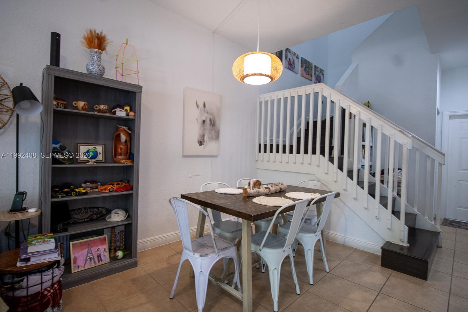 A dining area features a wooden table, white metal chairs, and a staircase nearby — 2607 SW 99th Way, Miramar FL 33025, MIRAMAR, FL