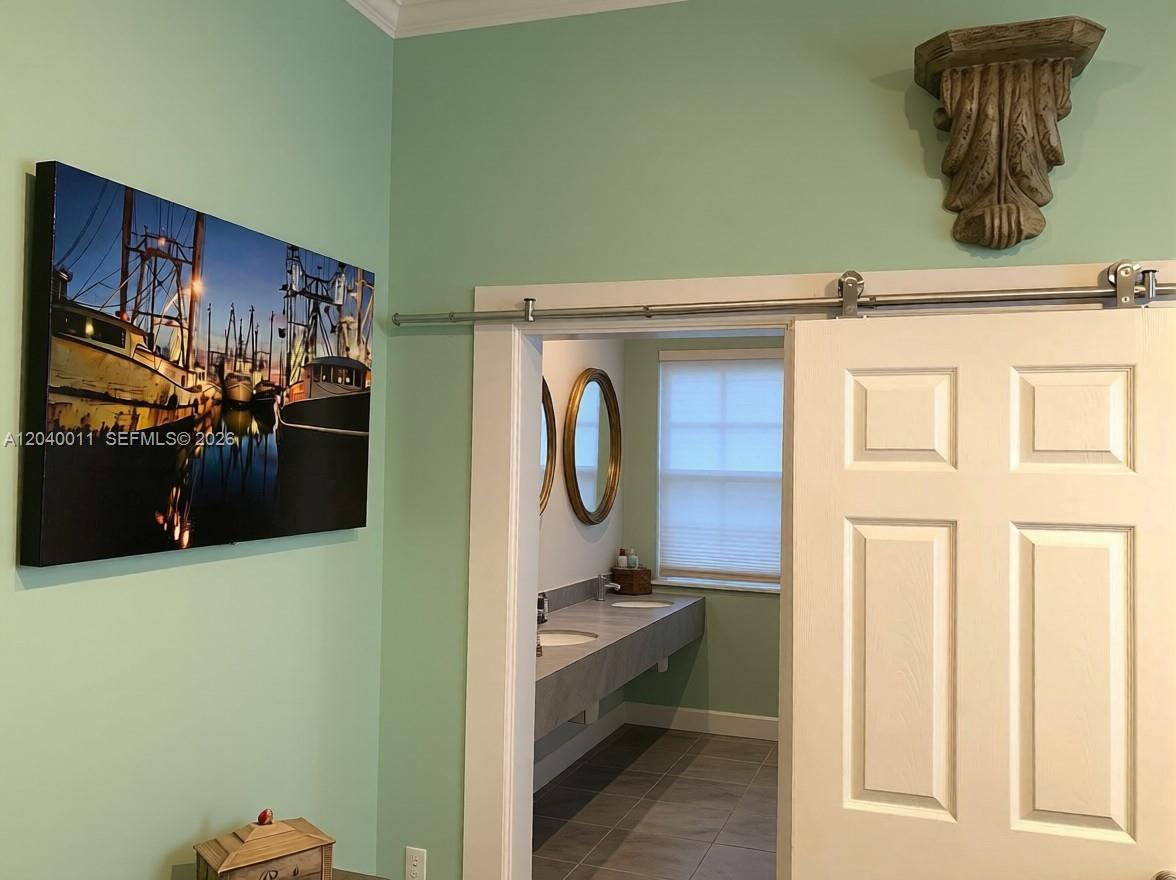 A sliding barn door opens to a bathroom with a double vanity and oval mirror — 1411 Truman Ave # 0, Key West FL 33040, KEY WEST, FL